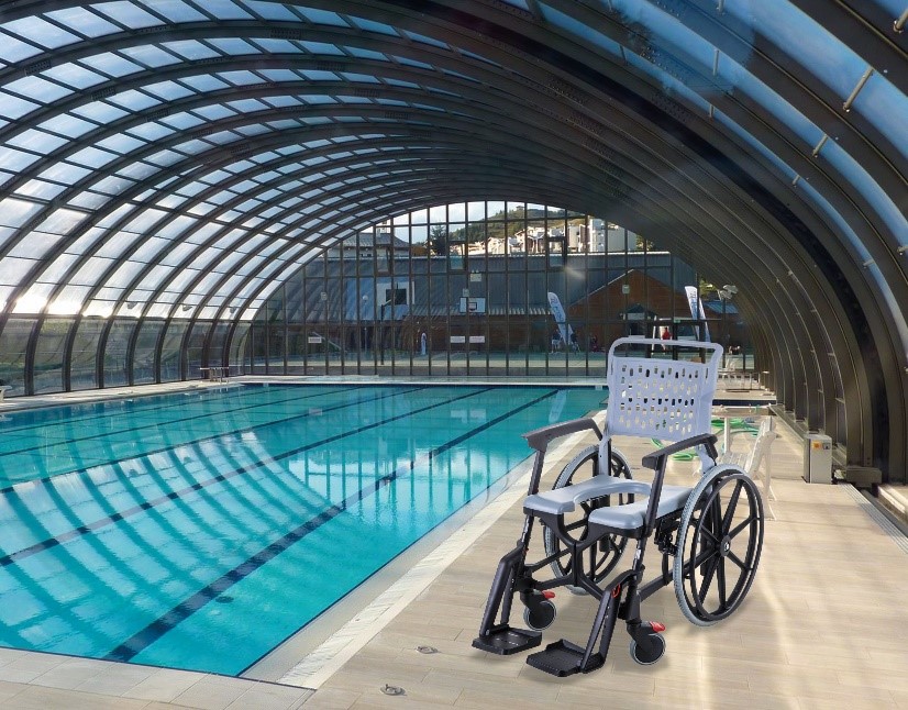 Un fauteuil d'aisance BathMobile est situé à côté d'un bassin intérieur de piscine publique