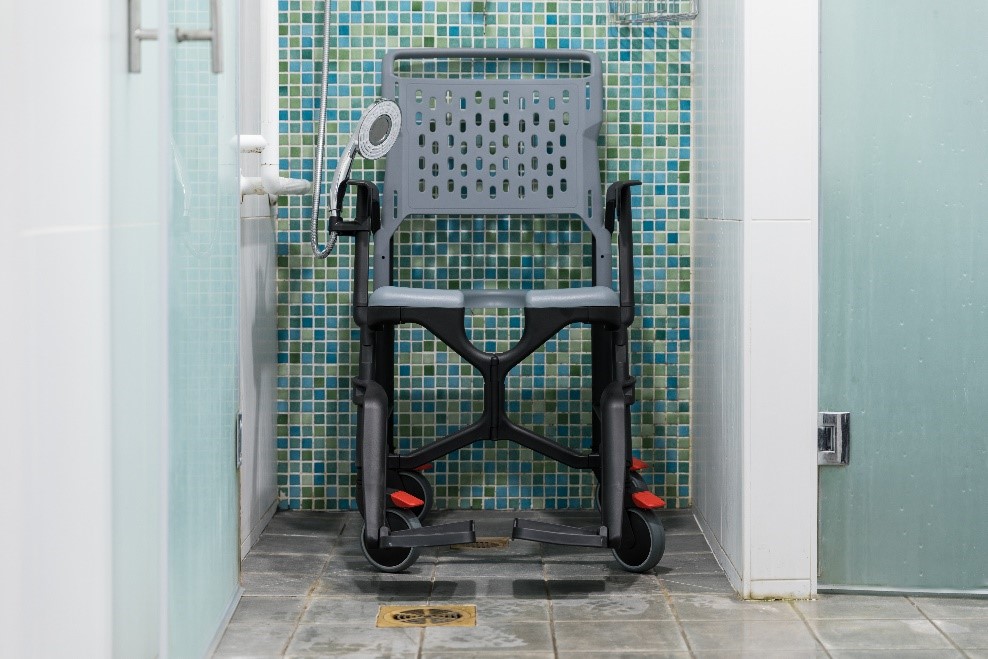 Un fauteuil Bathmobile est posé dans une douche à l'italienne