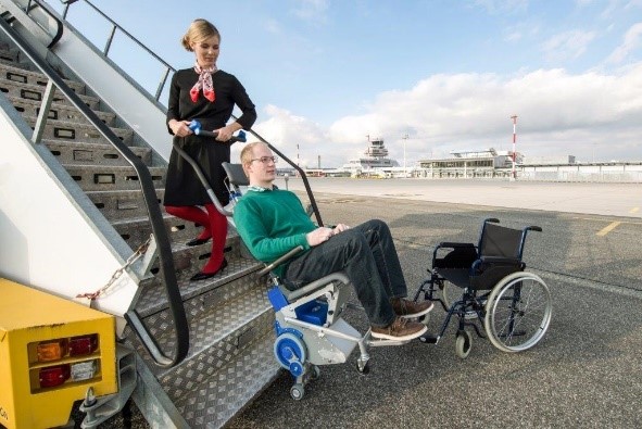 Une hôtesse de l'air manipule un monte-escaliers électrique PT Airport afin de faire accéder une personne en fauteuil roulant à la cabine de l'avion.