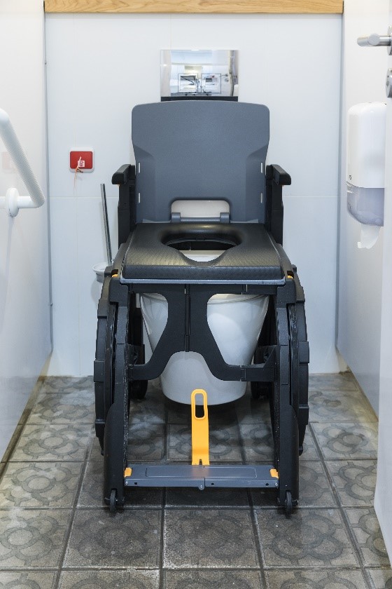 Un fauteuil Wheelable est placé par dessus des toilettes existantes pour donner l'accès à une personne à mobilité réduite.