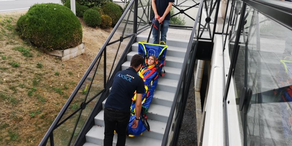 Deux aidants secouristes évacuent une personne en situation de malaise dans des escaliers via le matelas EvacPro