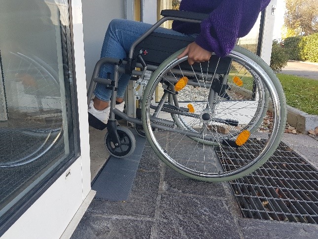 Une personne en fauteuil roulant accède à l'entrée d'une entreprise grâce à une mini-rampe en caoutchouc