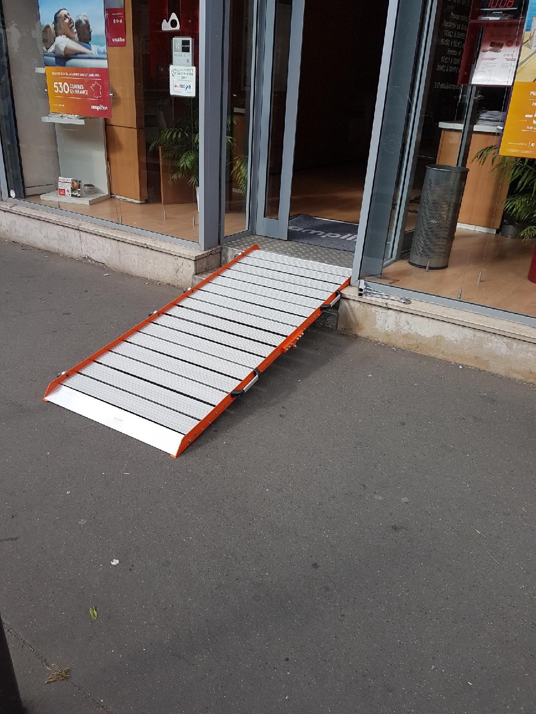 Une rampe d'accès PMR en aluminium posée sur la marche d'un établissement recevant du public