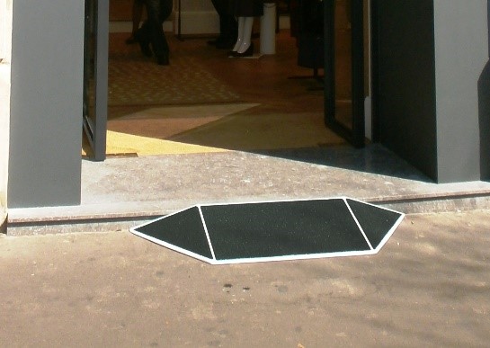 Une rampe de seuil évasée située au niveau de la marche d'entrée d'une boutique parisienne donne l'accès aux PMR