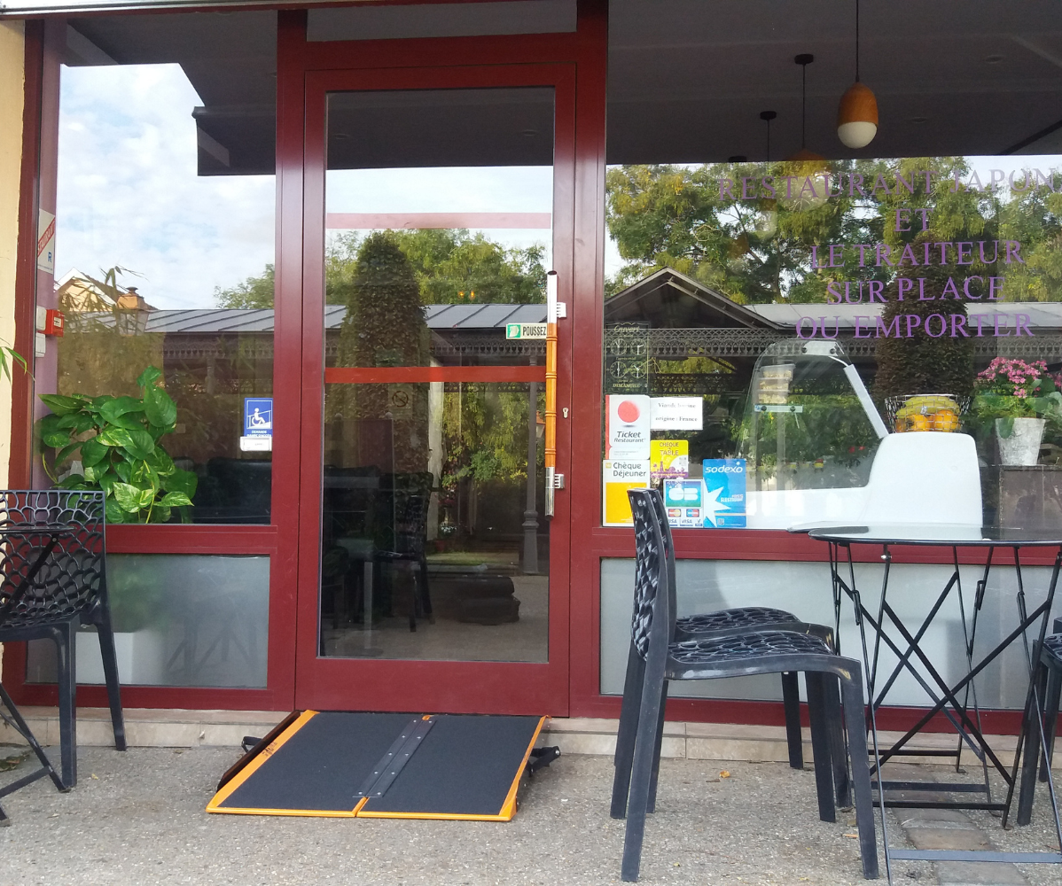 Une rampe d'accès Shop Ramp est posé sur la marche d'entrée d'un restaurant de nourriture asiatique.
