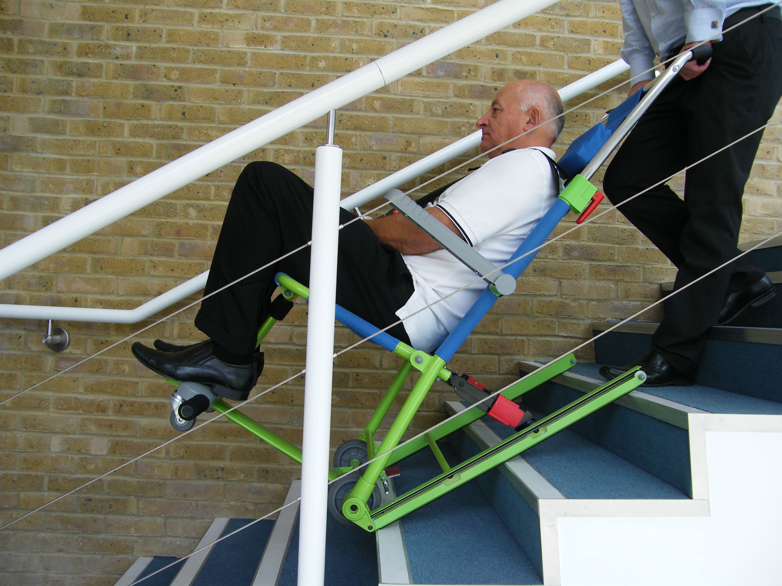Un aidant évacue une personne à mobilité réduite dans les escaliers grâce à la chaise Excel